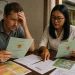 a foreign property buyer reviewing land certificates with a notary in Bali, with maps, zoning documents, and a villa site plan on the table, showing concern about legal risks.